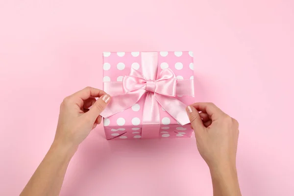 Weibliche Hände Und Geschenkbox Mit Schleife Auf Rosa Hintergrund — Stockfoto