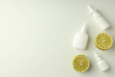 Boş burun spreyi şişeleri ve beyaz arka planda limon yarıları.