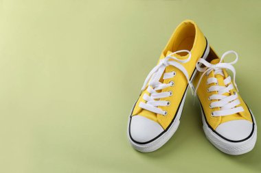 Yeşil arka planda bir çift sarı spor ayakkabı.