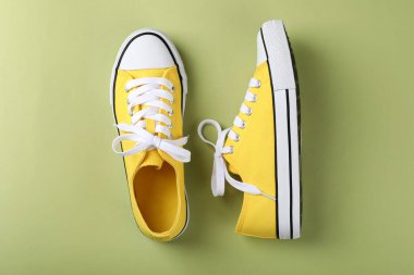 Yeşil arka planda bir çift sarı spor ayakkabı.