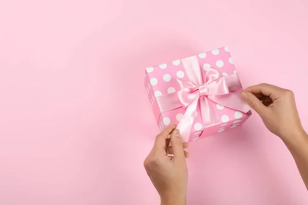 Weibliche Hände Und Geschenkbox Mit Schleife Auf Rosa Hintergrund — Stockfoto
