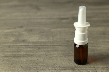 Gri desenli arka planda boş burun spreyi şişesi.