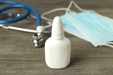 Gri dokuda burun spreyi, tıbbi maske ve steteskop.