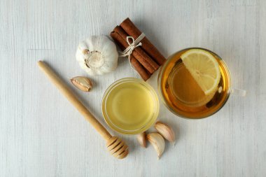 Beyaz ahşap arka planda bal ve sarımsak içeren soğuk algınlığı tedavisi kavramı
