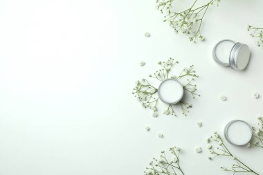 Beyaz arka planda eko dudak kremi ve çiçekler