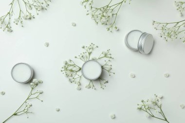 Beyaz arka planda eko dudak kremi ve çiçekler