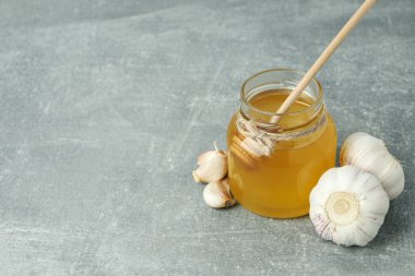 Gri dokulu arka planda bal ve sarımsaklı soğuk algınlığı tedavisi kavramı