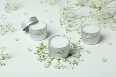 Beyaz arka planda eko dudak kremi ve çiçekler