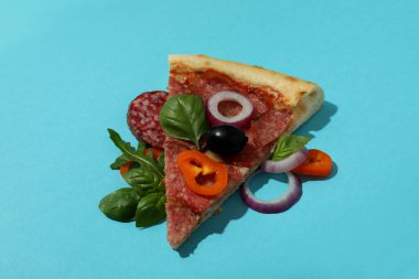 Mavi arka planda bir dilim salamlı pizza.