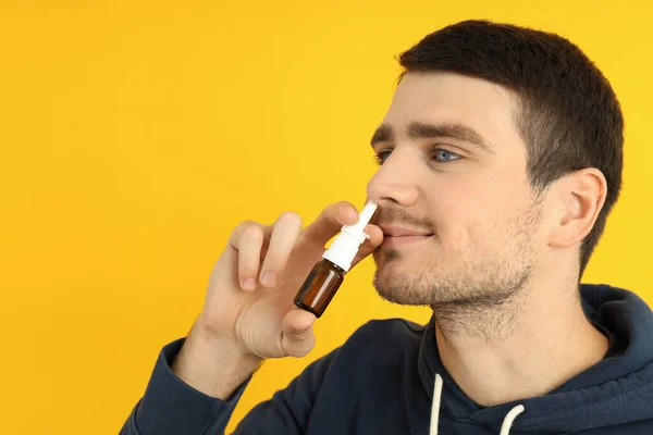 Hombre Joven Con Aerosol Nasal Sobre Fondo Amarillo Concepto Secreción — Foto de Stock