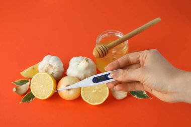 Turuncu arka planda bal ve sarımsak içeren soğuk algınlığı tedavisi kavramı