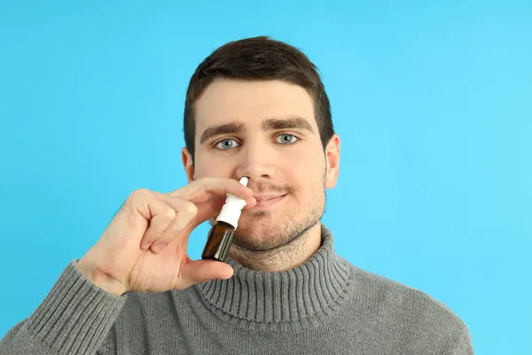Hombre Joven Con Aerosol Nasal Sobre Fondo Azul Concepto Secreción — Foto de Stock