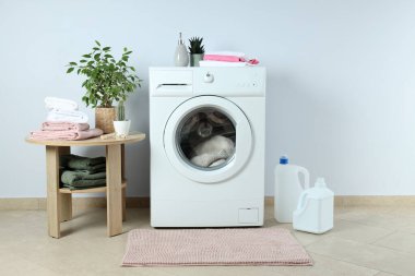 Beyaz duvara karşı çamaşır makinesiyle ev işi kavramı