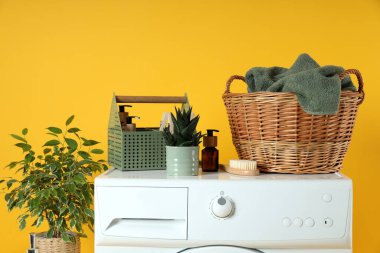 Sarı arka planda çamaşır makinesi olan ev işi kavramı