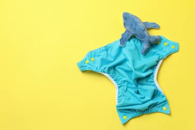 Sarı arka planda yeniden kullanılabilir bebek bezi olan bebek kıyafetleri kavramı