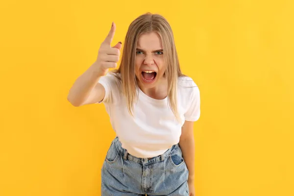 Sarı Arka Planda Kot Pantolonlu Genç Kızgın Kız — Stok fotoğraf