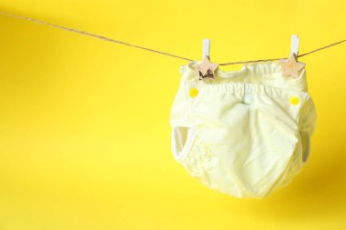 Sarı arka planda yeniden kullanılabilir bebek bezi olan bebek kıyafetleri kavramı