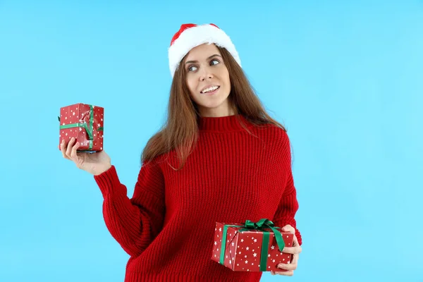 Attraktive Frau Mit Weihnachtsmütze Hält Geschenkboxen Auf Blauem Hintergrund — Stockfoto