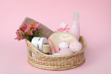 Pembe arka planda kozmetik ürünleri olan bir sepet.