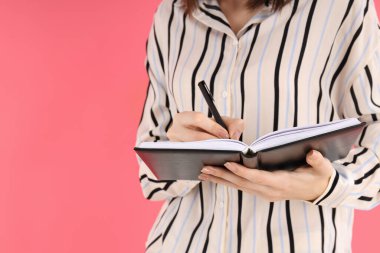 Pembe arka planda not alan bir kadın.