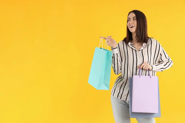 Aantrekkelijke Vrouw Met Winkeltassen Gele Achtergrond — Stockfoto