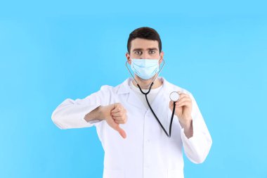 Mavi arka planda steteskobu olan genç bir doktor.