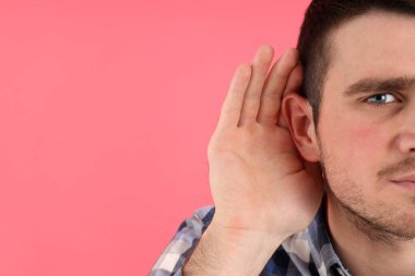 Pembe arka planda işitme sorunu olan genç bir adam.