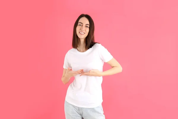 魅力的な女の子でホワイトTシャツ上のピンクの背景 — ストック写真