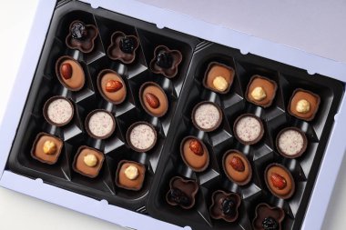 Beyaz arka planda kutuda çikolatalı şekerler, yakın plan.