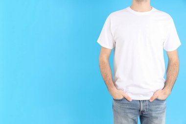 Mavi arka planda beyaz tişörtlü adam.