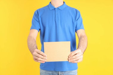 Sarı arka planda açık mavi polo giyen adam.