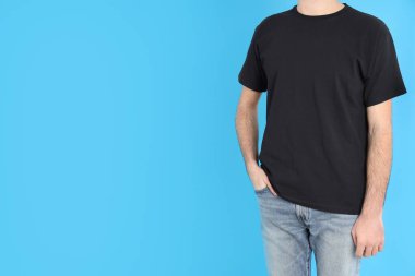Mavi arka planda siyah tişörtlü adam.