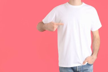 Pembe arka planda beyaz tişörtlü bir adam.