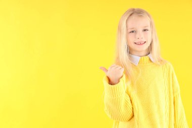 Sarı arka planda süveter giyen tatlı küçük kız.