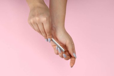 Pembe arka planda tırnak törpüsü olan kadın elleri