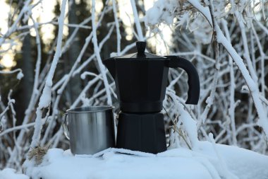 Kahve makinesi ve metal bardak, kış günü kütükte.
