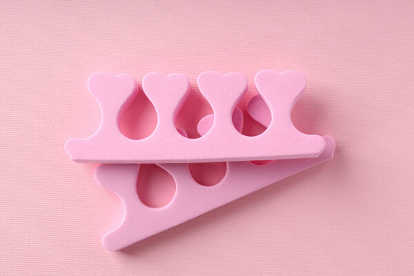 Pink nail separators on pink background, close up