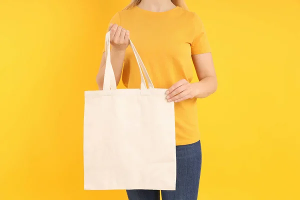 女人拿着黄色背景的空白棉包 — 图库照片