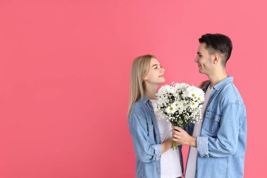Pembe arka planda buketi olan sevimli bir çift.