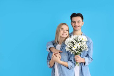 Mavi arka planda buketi olan sevimli bir çift.