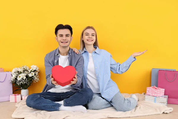 Bonito Feliz Casal Sentado Contra Fundo Amarelo — Fotografia de Stock