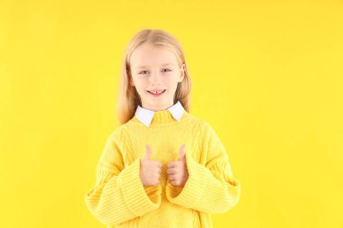 Sarı arka planda süveter giyen tatlı küçük kız.