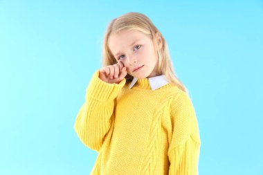 Mavi arka planda süveter giyen gücenmiş küçük kız