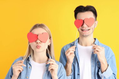 Sarı arka planda kalpleri olan sevimli bir çift.
