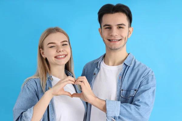 Casal Bonito Mostrando Sinal Amor Fundo Azul — Fotografia de Stock