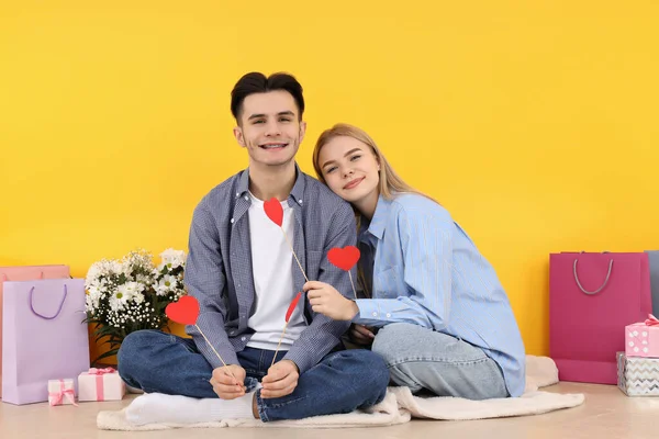 Sarı Arka Planda Oturan Sevimli Mutlu Bir Çift — Stok fotoğraf