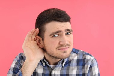 Pembe arka planda işitme sorunu olan genç bir adam.
