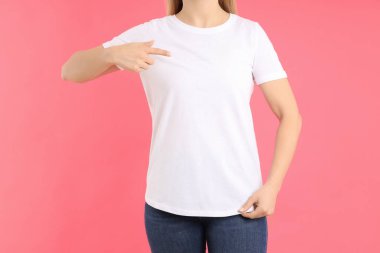 Pembe arka planda beyaz tişörtlü kadın.