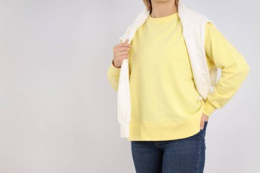 Açık gri arka planda, boş kazaklı bir kadın.