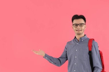 Pembe arka planda sırt çantası olan erkek öğrenci.